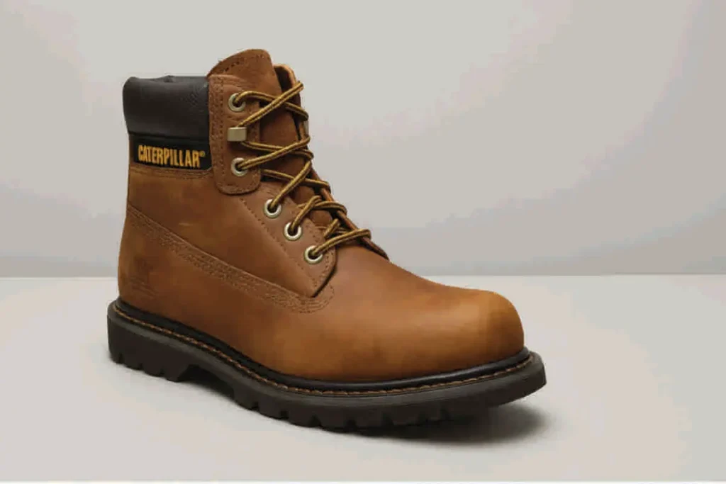 Bota de trabajo Caterpillar Second Shift de cuero marrón claro, con suela negra y cuello acolchado, diseñada para condiciones de obra pesada.