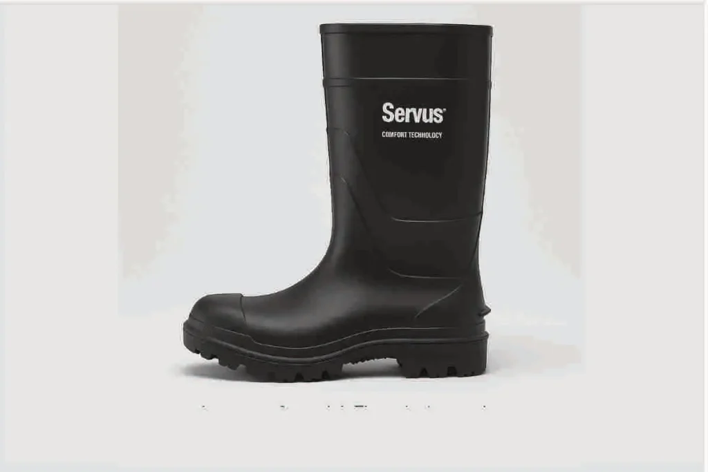 Bota impermeable Servus Comfort Technology negra, con diseño robusto y suela de tracción profunda, sobre fondo gris claro y leyenda de advertencia por variación de producto.