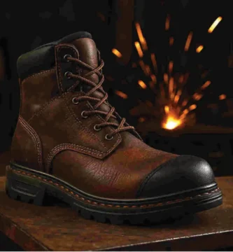 Bota de trabajo de cuero diseñada para soldadores, sobre superficie metálica con chispas de fondo, mostrando su diseño resistente al calor y la suela reforzada.